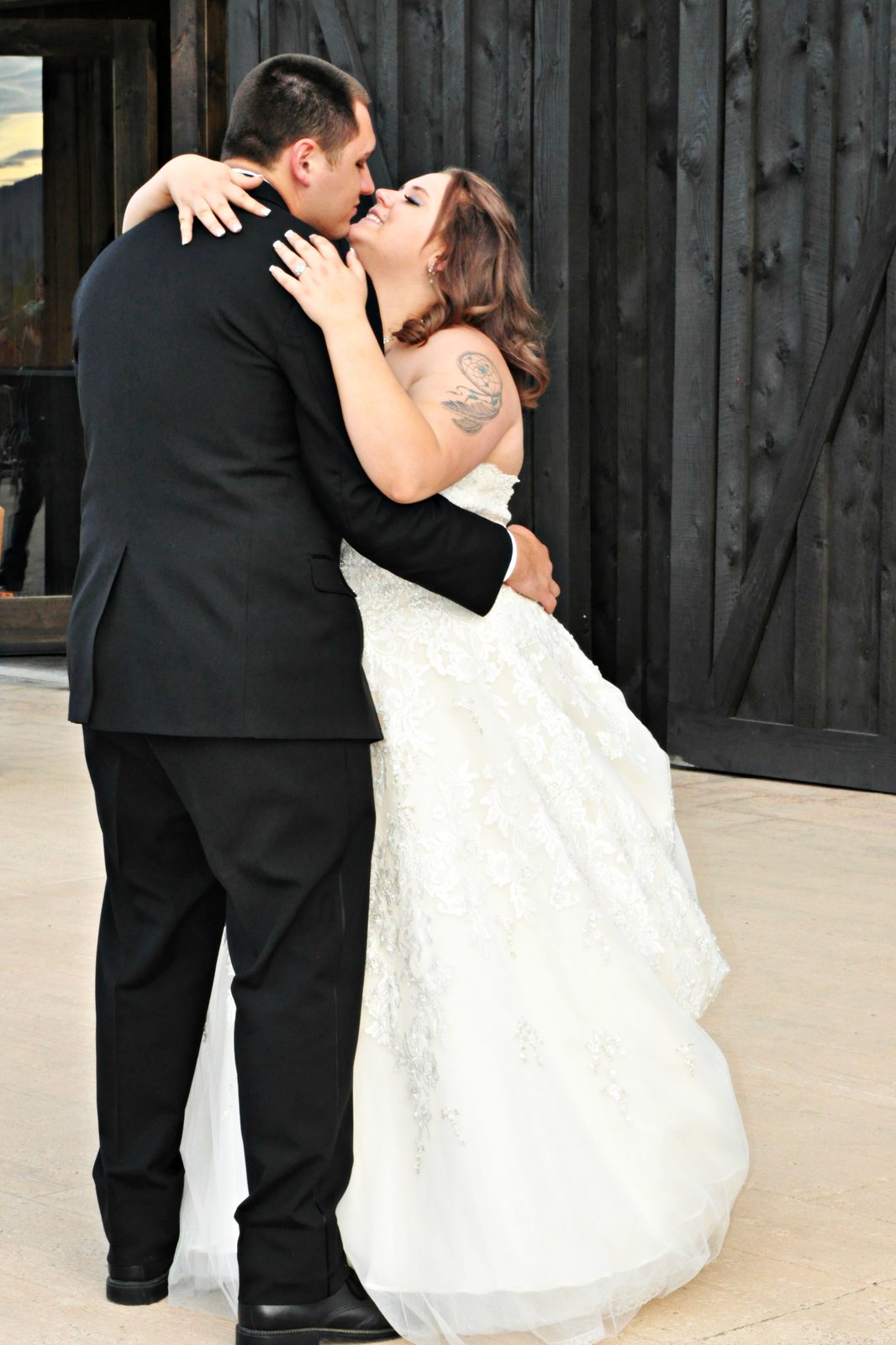 Couple nose to nose by black barn doors at golden hour
